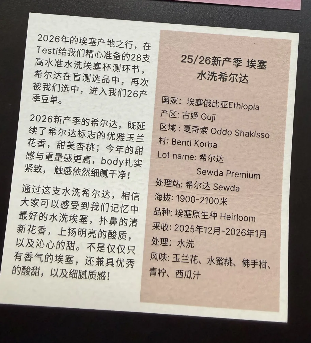 A printed card from Big Sur Coffee lying on a dark table, in Chinese and English. The spec column reads: Country Ethiopia, Region Guji, Area Oddo Shakisso, Village Benti Korba, Lot name Sewda Premium, washing station Sewda, elevation 1900-2100 metres, variety Ethiopian Heirloom, harvest December 2025 to January 2026, process washed, flavors magnolia flower, honey peach, bergamot, lime and watermelon juice. The facing paragraphs describe Testi preparing a cupping of 28 high-standard washed Ethiopians on Big Sur's 2026 origin trip, Sewda being picked again in blind selection, and this year's crop keeping its magnolia florals and sweet apricot with more sweetness and weight than before.