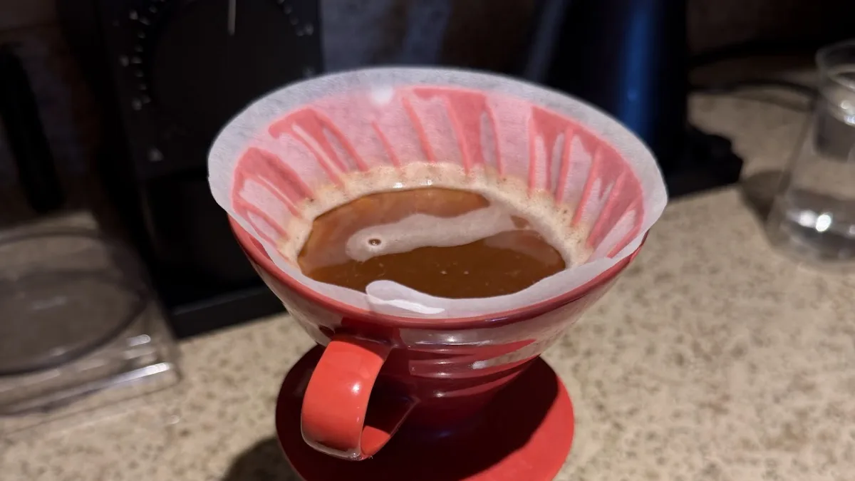 Looking down into a red Hario V60 partway through a 4:6 brew, the coffee bed flat under a layer of water.